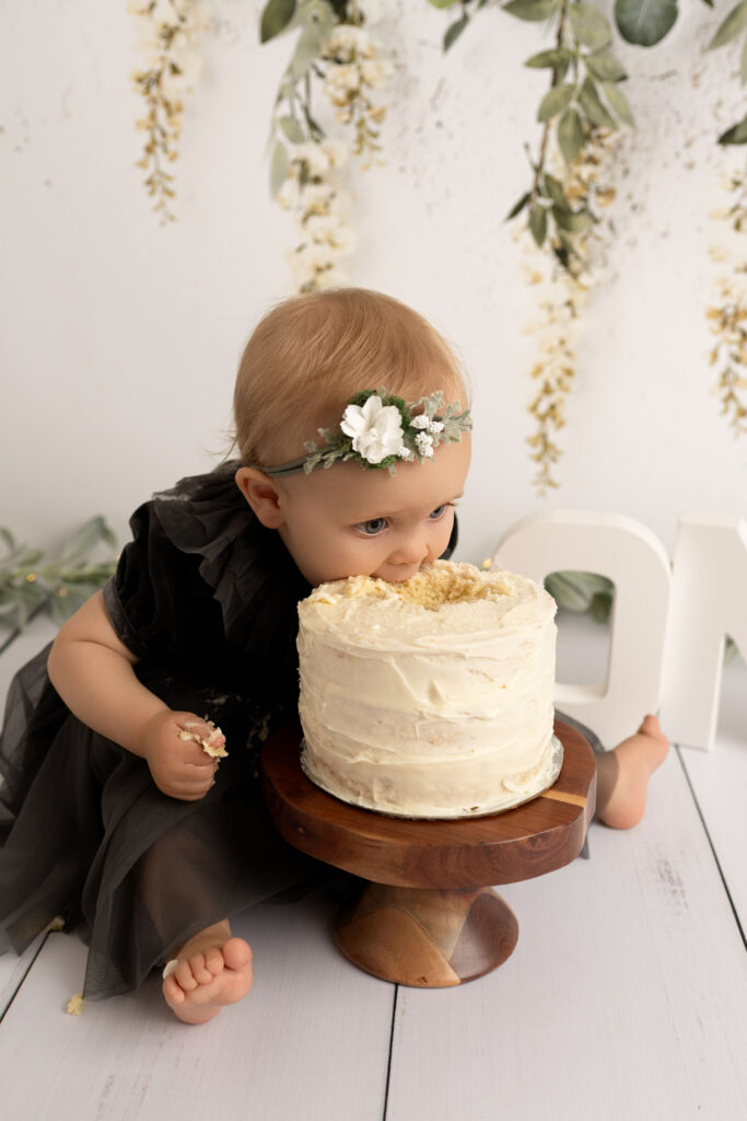 baby girl in simple boho theme cake smash in black dress getting messy with her cake smash in tri cities wa