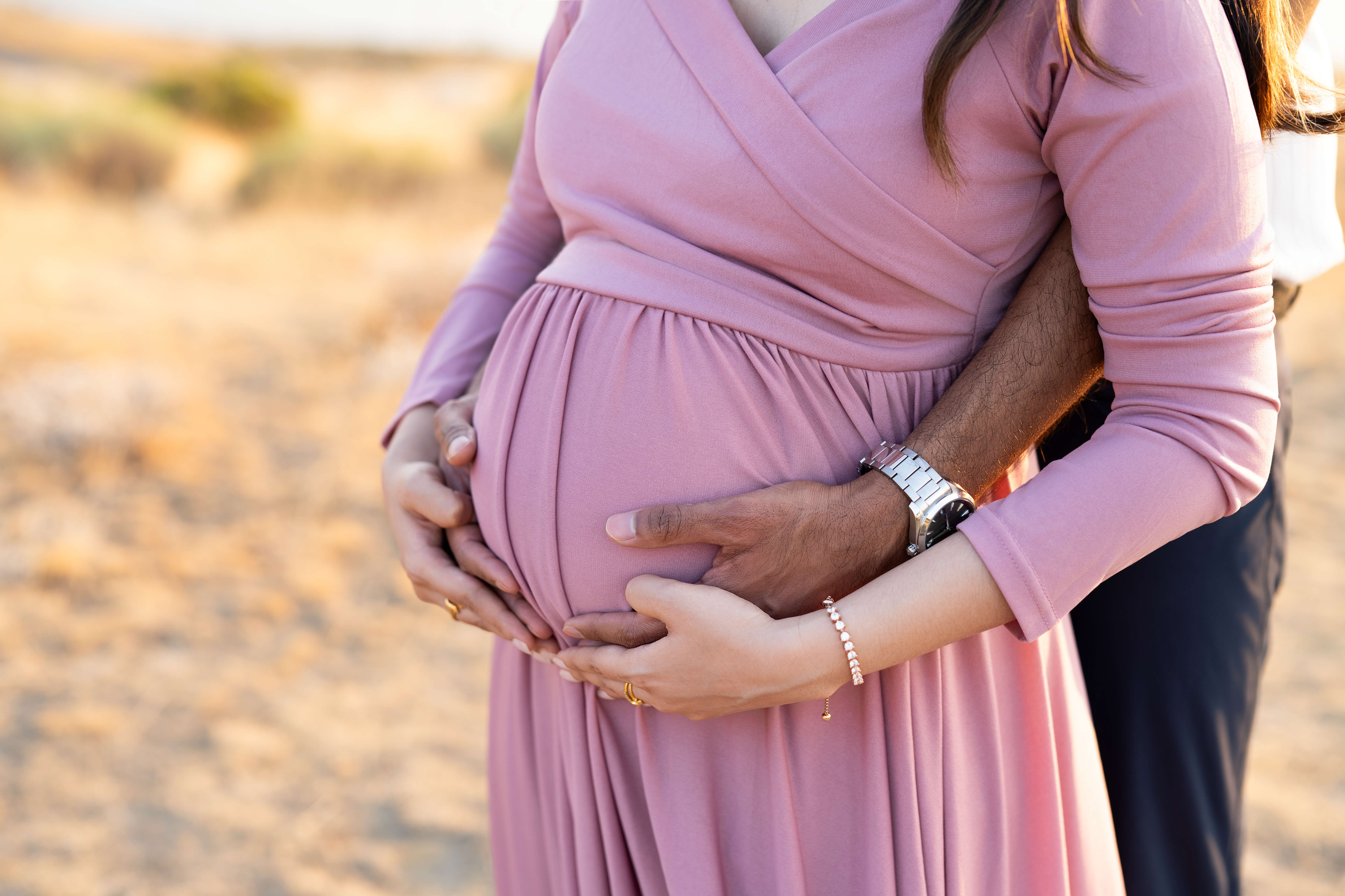 Details of an expecting couple hugging the bump