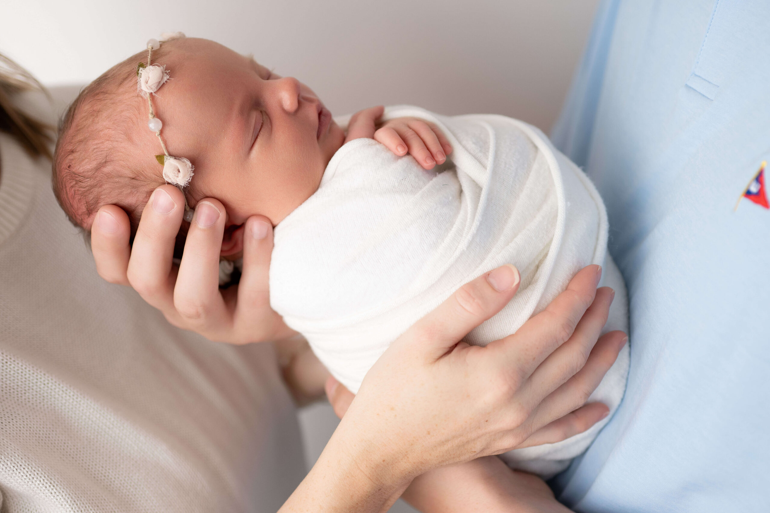 A newborn baby sleeping in mom and dad's hands in a white swaddle after meeting a nanny in tri-cities, WA